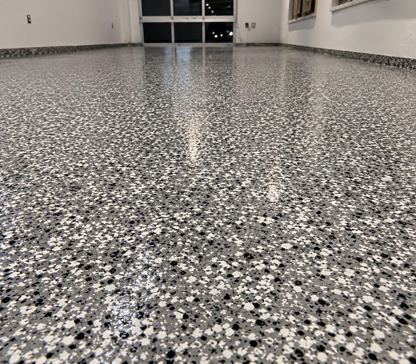 Close-up of a black, white, and gray full-broadcast flake concrete coating
